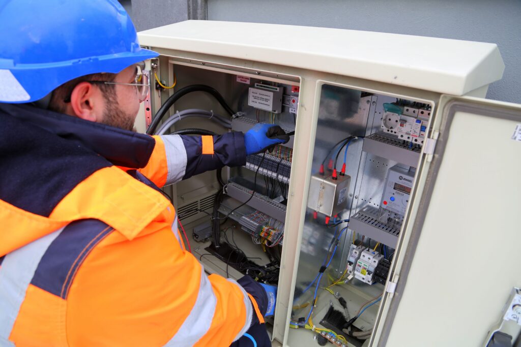 Home Engineer in safety gear working on an outdoor electrical panel, ensuring system functionality.